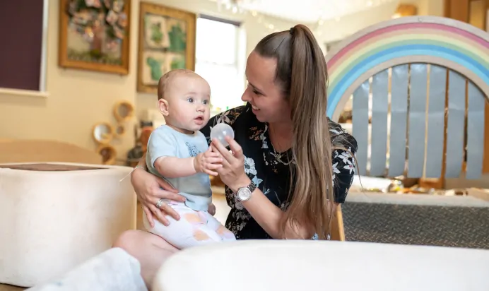 Key worker playing with baby at Dicky Birds Nursery Preschool Raynes Park London