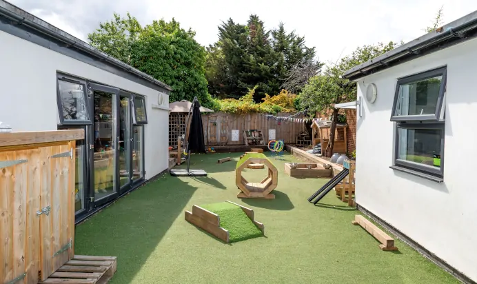 Outdoor play area with wooden tunnel and sand pit at Dicky Birds Nursery Preschool Queens Road Wimbledon London