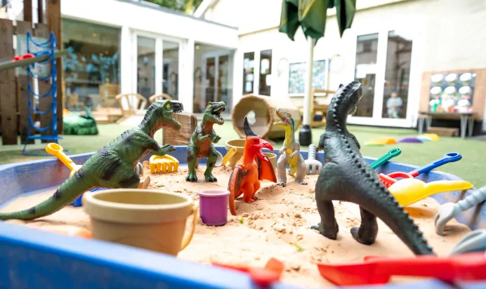 Toy dinsoaurs in a sandpit at Dicky Birds Nursery Preschool Claremont Road Surbiton