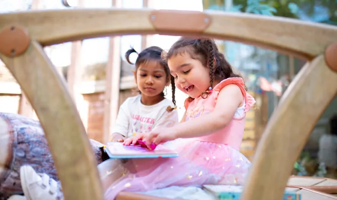 Two children reading a book at Dicky Birds Nursery Preschool Claremont Road Surbiton