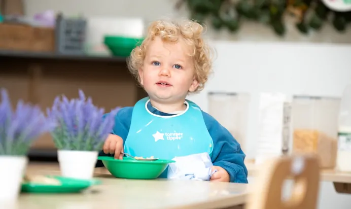 Young child eating breakfast at Dicky Birds Nursery Preschool Queens Road Wimbledon London