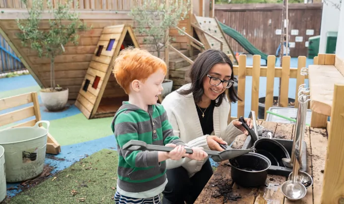 Child and key worker playing in outdoor play kitchen at The Winchmore Hill Day Nursery London