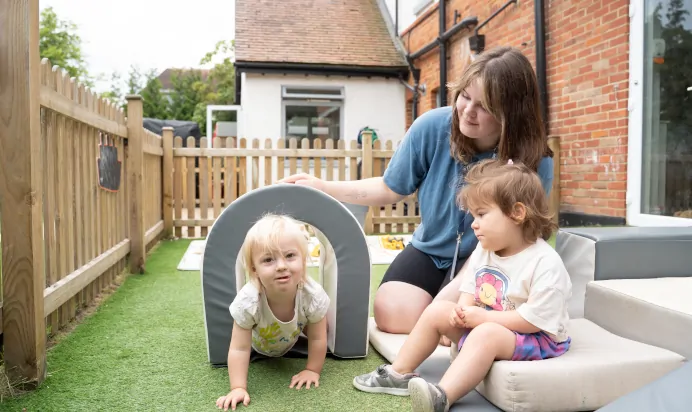 Child crawling through tunnel outside at The Daydream Nursery Preschool Woking