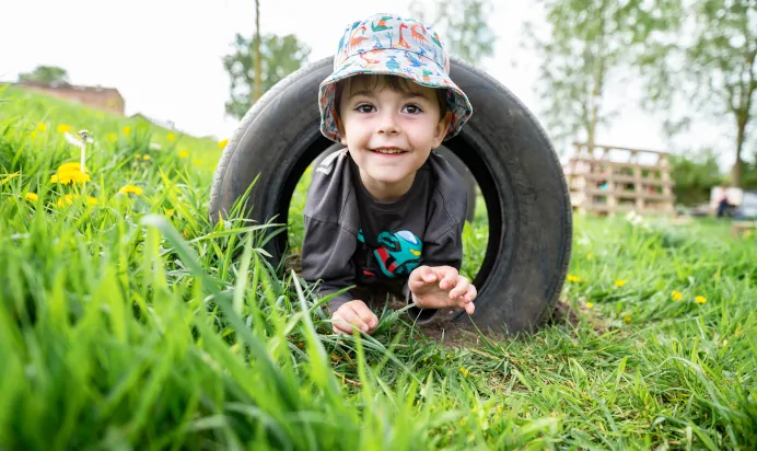 Child crawling through tyre at Pippins Montessori Day Nursery Forest School Colchester