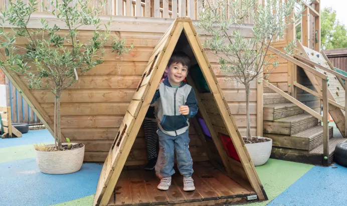 Child in wooden teepee at The Winchmore Hill Day Nursery London