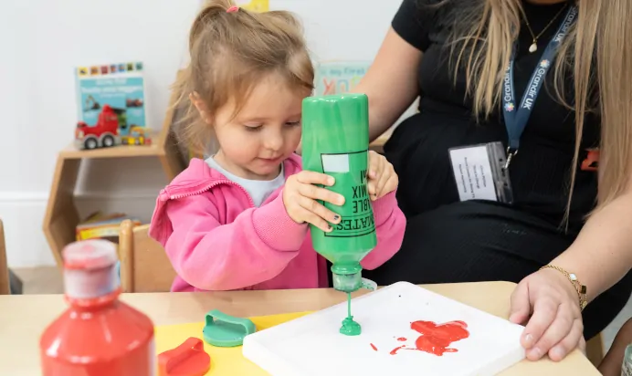 Child painting with key worker at The Chingford Forest Day Nursery Preschool London