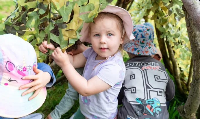 Child playing in tree teepee at Pippins Montessori Day Nursery Forest School Colchester