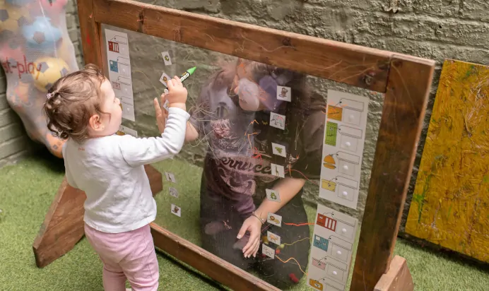 Child playing with keyworker in outside space at The Kensington Place Nursery Preschool London
