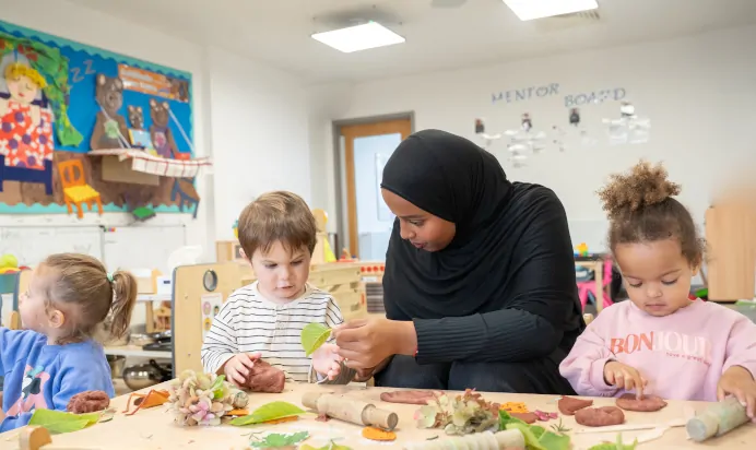 Child playing with leaves at The Winchmore Hill Day Nursery London