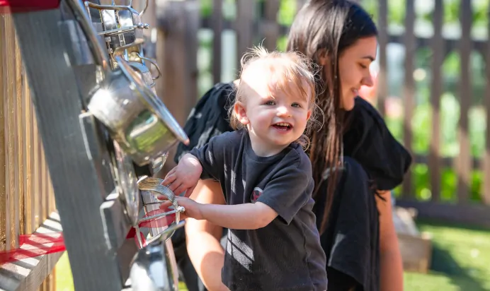 Child playing with pots and pans making music with key worker at Pippins Montessori Day Nursery Forest School Colchester