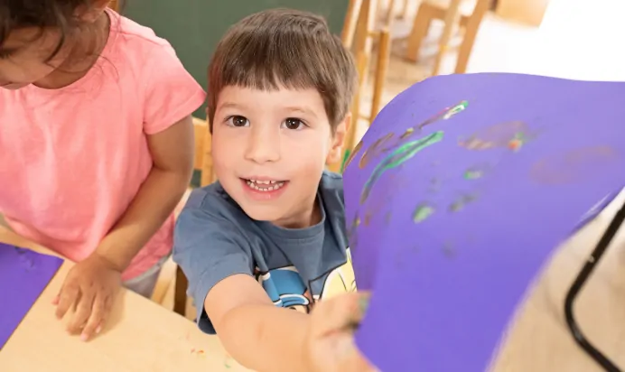 Child showing off drawing at The West Finchley Day Nursery Preschool London