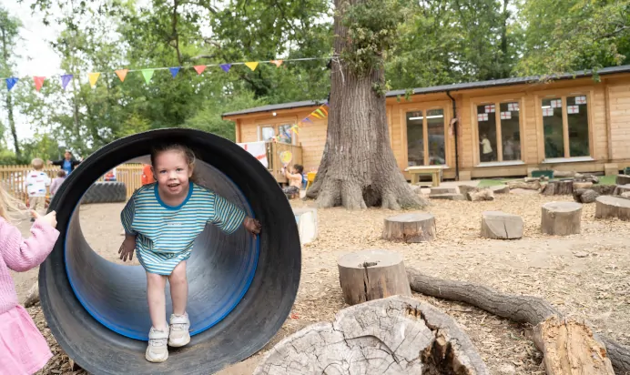 Child smiling in tunnel at The Chingford Forest Day Nursery Preschool London