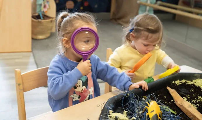 Child with magnifying glass at The Winchmore Hill Day Nursery London