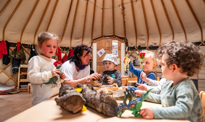 Children and key worker playing with toys and pinecones at Pippins Montessori Day Nursery Forest School Colchester