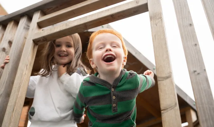 Children laughing on play equipment at The Winchmore Hill Day Nursery London