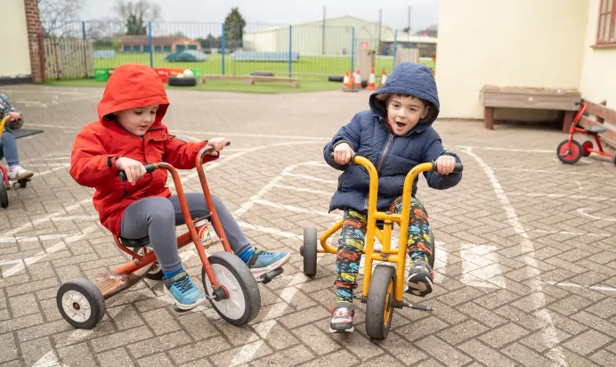 Children playhing on tricycles at The Ryan House Day Nursery Preschool Nottingham