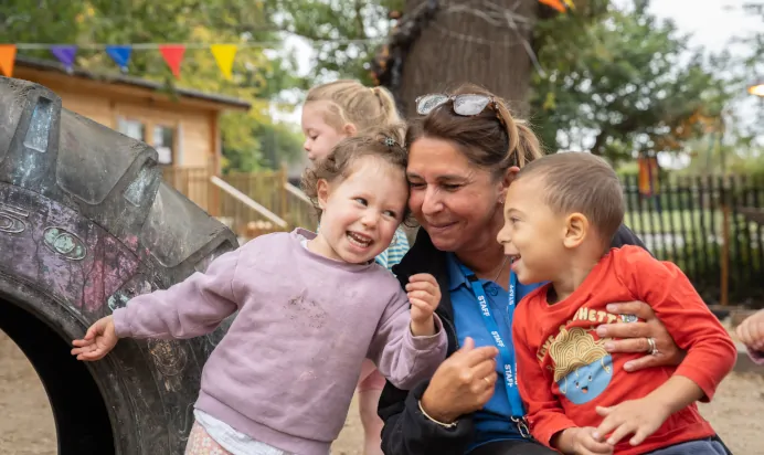 Children playing together with key worker outside at The Chingford Forest Day Nursery Preschool London