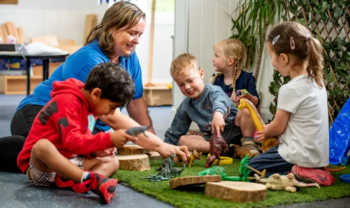 Children playing with key worker and toy dinosaurs at Radcliffe On Trent Day Nursery Preschool