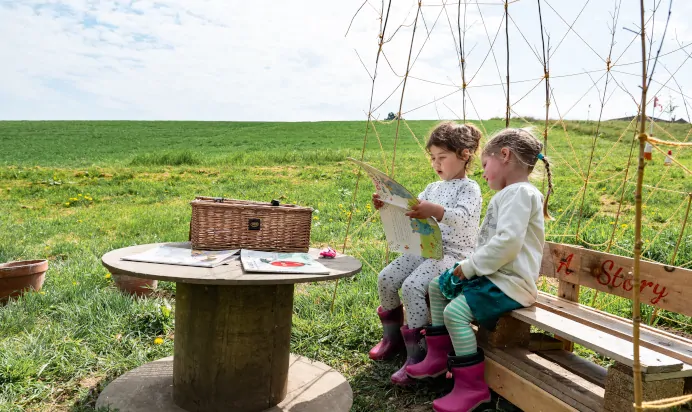 Children reading together outside at Pippins Montessori Day Nursery Forest School Colchester