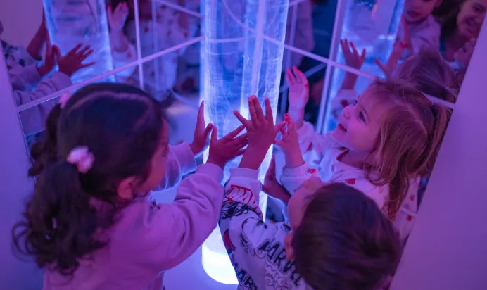 Children smiling with blue light projector at The Wandsworth Day Nursery Preschool London