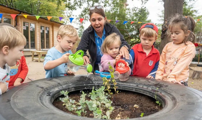 Children watering plants with key worker at The Chingford Forest Day Nursery Preschool London