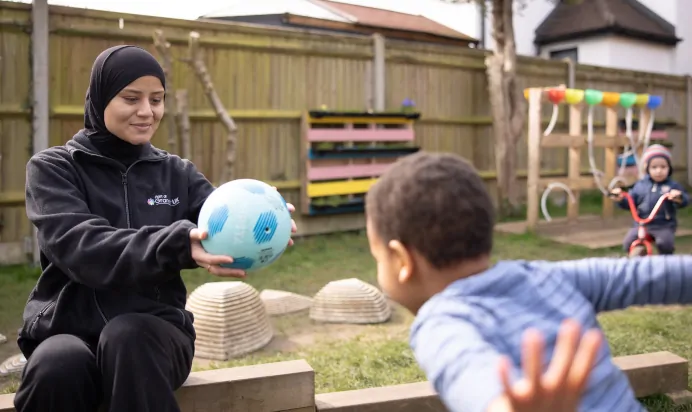 Key worker and child playing with football at The Harpenden Day Nursery Preschool