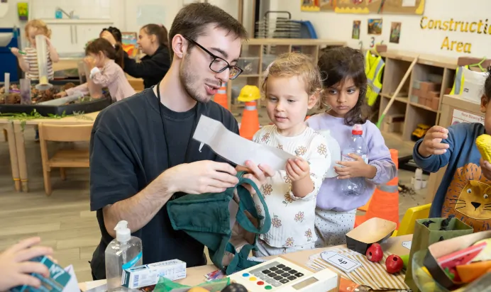 Key worker and child reading paper at The Winchmore Hill Day Nursery London