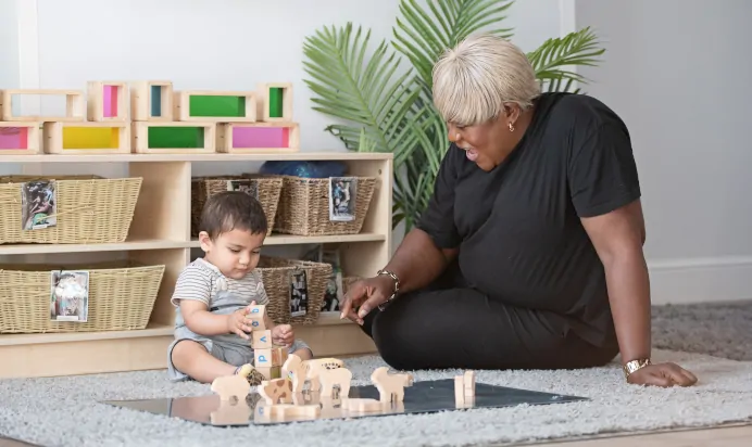 Key worker and childing playing with wooden blocks at Clerkenwell Mount Day Nursery Preschool London