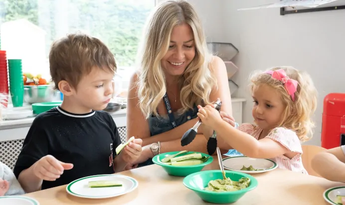 Key worker and children eating lunch at The Daydream Nursery Preschool Woking