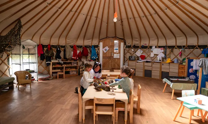 Key worker and children playing at table at Pippins Montessori Day Nursery Forest School Colchester