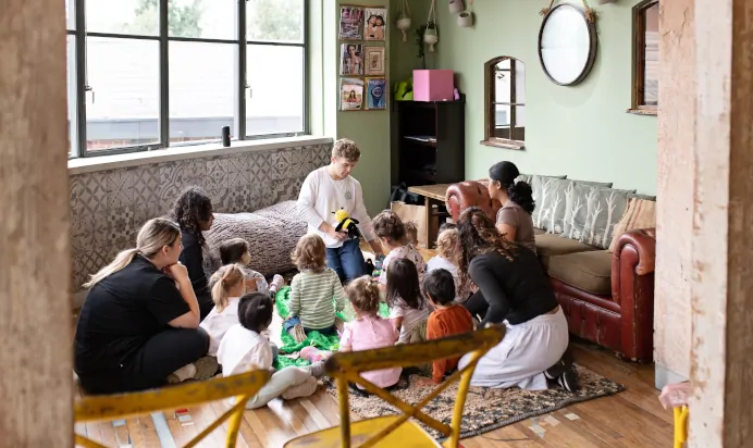 Key worker entertaining children with soft toys at The Chiswick House Day Nursery Preschool London