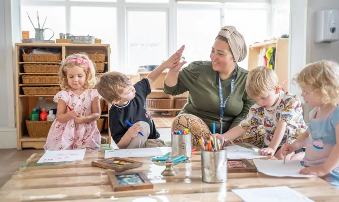 Key worker high fiving child at The Daydream Nursery Preschool Woking