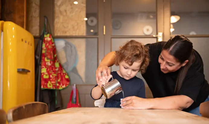 Key worker pouring water with child at The Chiswick House Day Nursery Preschool London