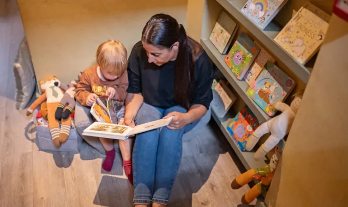 Key worker reading a book with child at The Kensington Place Nursery Preschool London