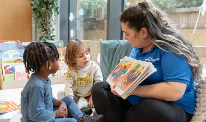 Key worker reading a book with child at The Wandsworth Day Nursery Preschool London