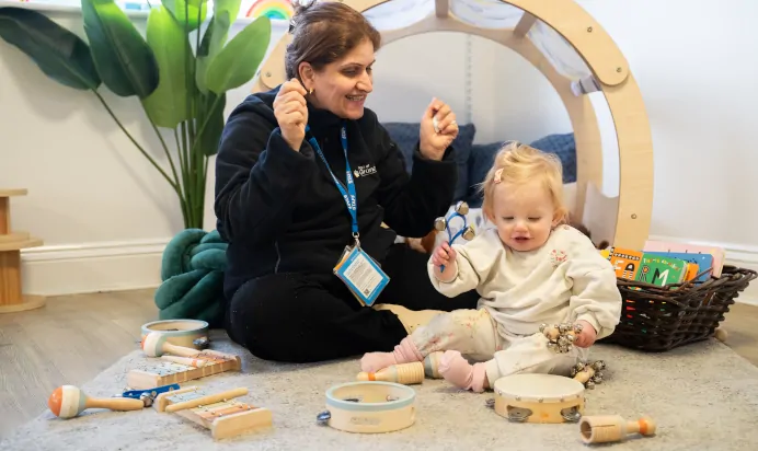 Keyworker and child playing with musical instruments at The Ryan House Day Nursery Preschool Nottingham