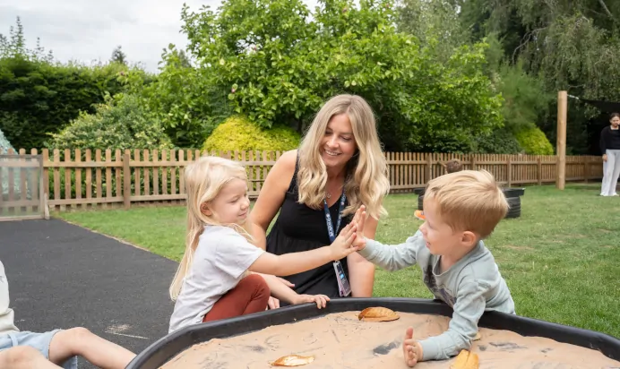 Two children high fiving outside at The Daydream Nursery Preschool Woking