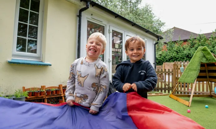 Children laughing while playing with parachute at The Wishing Tree Nursery Preschool Brighton