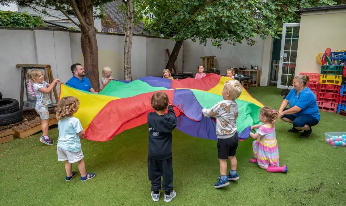 Children playing outside with parachute at The Wishing Tree Nursery Preschool Brighton