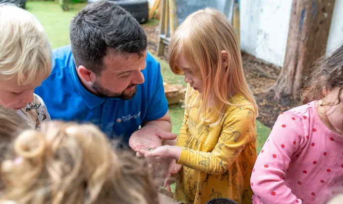 Key worker getting seeds from child at The Wishing Tree Nursery Preschool Brighton