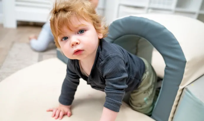 Child crawling out of play tunnel at Kiddi Caru Day Nursery Preschool Brislington Bristol