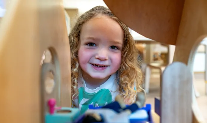Child playing and smiling to the camera at Kiddi Caru Day Nursery Preschool Crews Hole Bristol