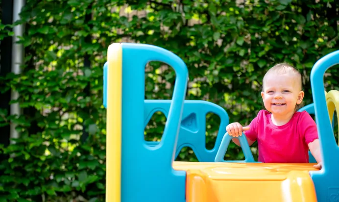 Child playing on outdoor playground equipment at Kiddi Caru Day Nursery Preschool Soundwell Bristol