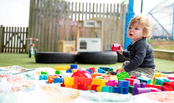 Child playing with building blocks outside at Kiddi Caru Day Nursery Preschool Brislington Bristol