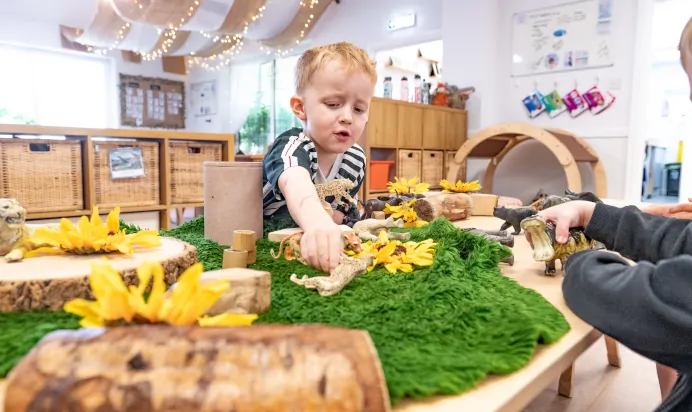 Child playing with dinosaurs at Kiddi Caru Day Nursery Preschool Crews Hole Bristol