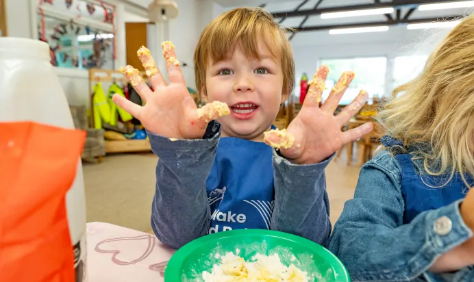 Child showing hands covered in dough at Kiddi Caru Day Nursery Preschool Crews Hole Bristol
