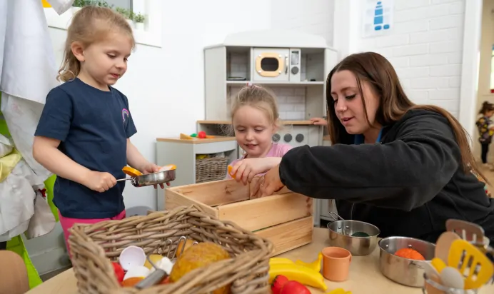 Children and key worker playing pretend cooking at Kiddi Caru Day Nursery Preschool Brislington Bristol
