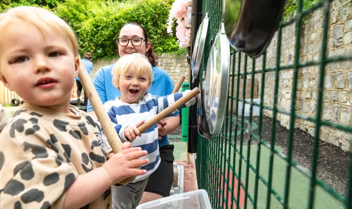Children making music with pots and pans with key worker at Kiddi Caru Day Nursery Preschool Crews Hole Bristol