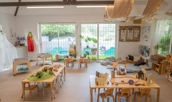 Indoor play area with book corner and cars and dinosaur toys at Kiddi Caru Day Nursery Preschool Crews Hole Bristol