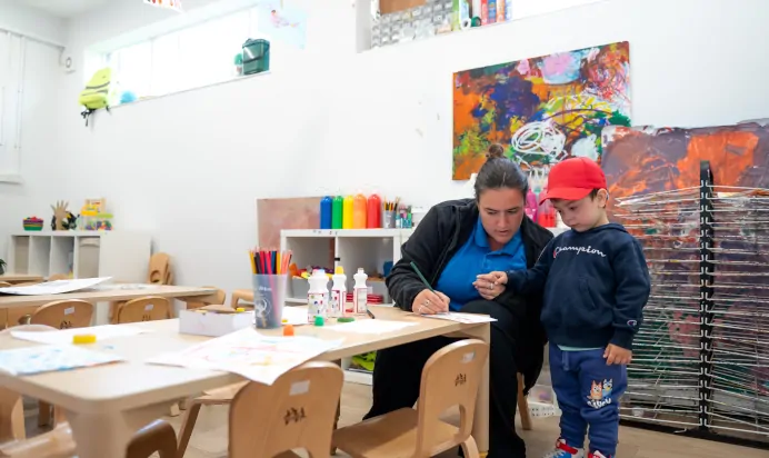 Key worker and child colouring inside at Kiddi Caru Day Nursery Preschool Brislington Bristol